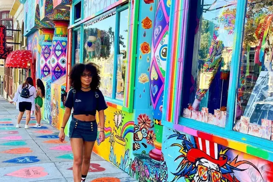 A woman walks down a street with colorful buildings 在贝博体彩app's 嬉皮 neighborhood.