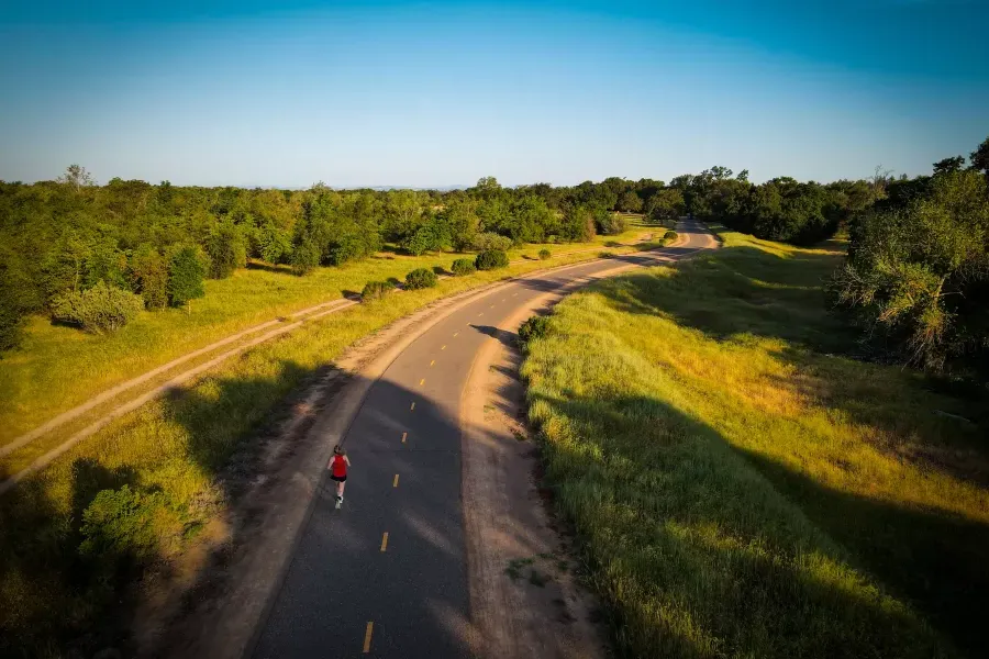 Overhead shot of woman running on a road through the countryside